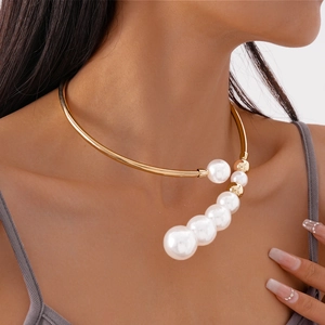 Close-up of a gold metal choker necklace featuring a gradient of white pearls on a model