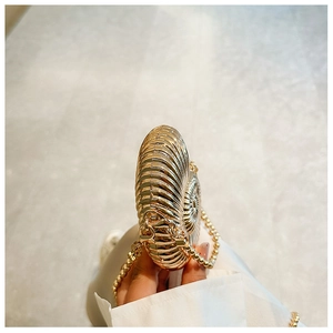Detail view of mini shell shaped metal handbag with spiral texture and gold bead chain