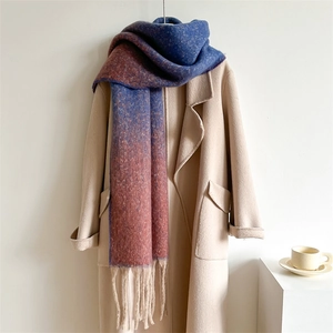 Detail of blue and red gradient scarf with fringe on a beige coat in a warm setting