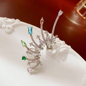 Close-up of silver ear cuff with colorful gemstones and crystals on white relief plate