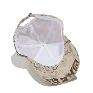 Detail of distressed beige baseball cap featuring ripped holes and vintage graffiti print