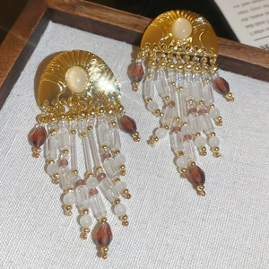 Detailed view of vintage tassel earrings with pearls and amber crystals on beige fabric