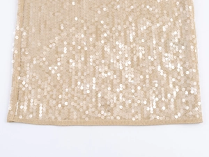 Close-up of golden sequins and needlework on a stylish lace dress with metallic shimmer