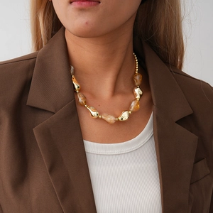 Close-up of women wearing gold metal beads and amber acrylic irregular geometric necklace