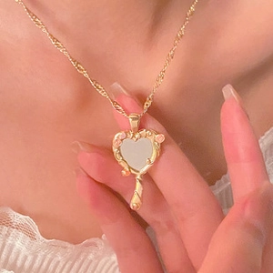 Close-up of heart-shaped hand mirror necklace with pink flowers on gold rope chain