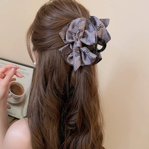 Close-up of a large bow hair claw clip in dark brown fabric with black ribbon patterns