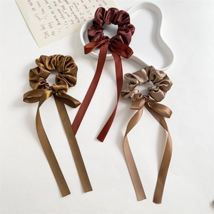 Flat lay of satin scrunchies with long ribbons in brown and champagne earth tones