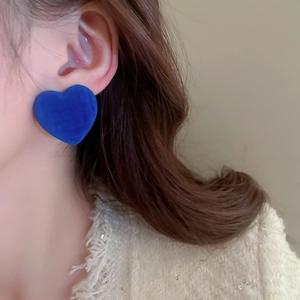 Close-up of blue flocked heart earrings on model showing retro velvet texture