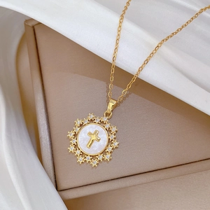 Detail of gold star cross necklace with pearl shell inlay and shimmering crystal accents