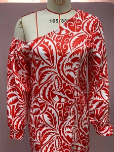 Détail de l'imprimé feuille rouge sur robe asymétrique à une épaule et manches longues