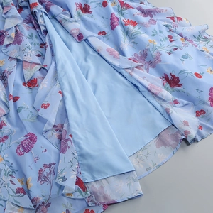 Detail von floralem Chiffon-Stoff mit gestuften Rüschen und hellblauem Innenfutter