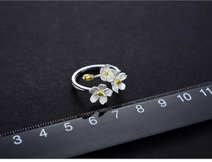 Macro shot of silver forget-me-not flower ring with gold stamens and petal details
