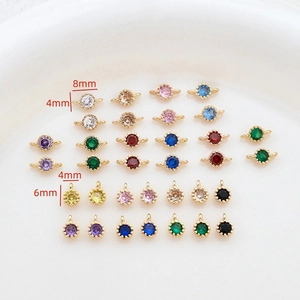 Detail of 4mm to 8mm colorful zircon gold plated pendants on a white jewelry tray
