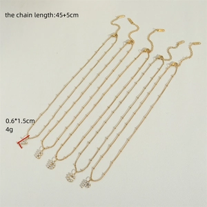 Detail view of gold letter pendants with pearls showing sizes 45+5cm and 0.6x1.5cm