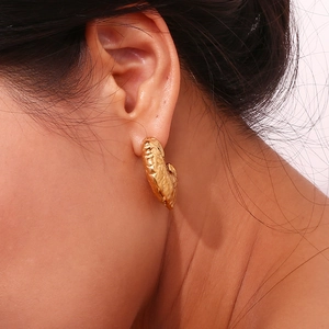 Close-up of a 18K gold-plated heart earring with hammered texture on female earlobe