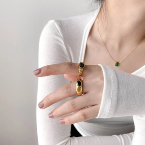 Detail of vintage gold rings with black gemstones on a model's hand in minimalist style