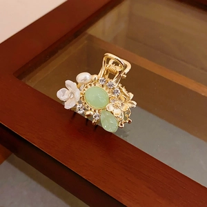 Macro view of vintage gold flower hair claw with pearl tassels and emerald resin stones