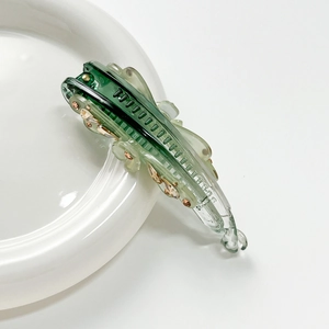 Close-up of elegant green crystal flower banana clip on a ceramic plate detail
