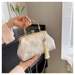 Close-up of white lace jacquard clutch with vintage metal clasp and elegant fringe
