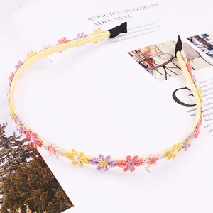 Detail of light yellow headband with colorful embroidered daisy flowers on a magazine