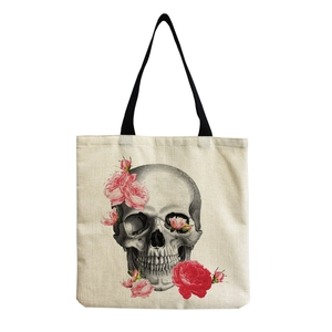 Close-up of skull and pink rose print on beige canvas tote bag with black strap