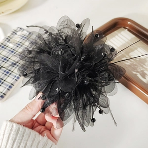 Detail of a black mesh flower hair claw clip with beads and delicate feather accents
