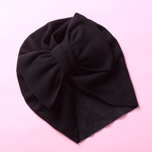 Detail view of black baby turban hat with large double-layer bow and pleated design