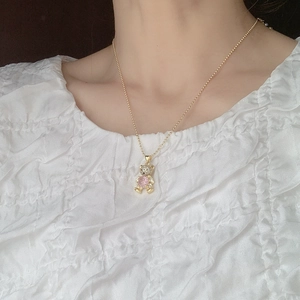 Close-up of golden bear pendant with white rhinestones and a pink gemstone on a necklace