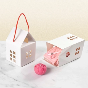 White house-shaped paper gift boxes with red rope handles and hollow heart patterns