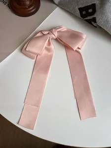 Détail d'une élégante pince à cheveux nœud en satin rose pâle avec de longs rubans