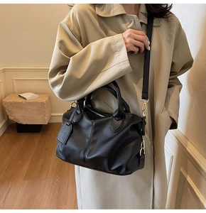 Detail of black pebbled leather Boston bag with dual handles and adjustable strap