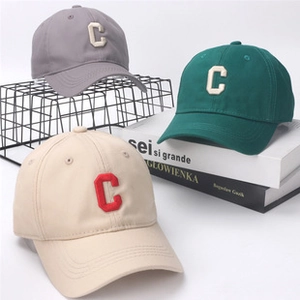 Detailed close-up of grey, green and beige cotton baseball caps with C embroidery