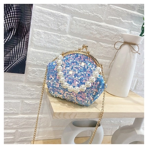 Detail of blue sequined shell bag featuring a pearl handle and golden chain strap