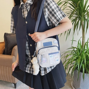 Détail d'un petit sac bandoulière blanc en toile avec écussons mignons et ours en peluche