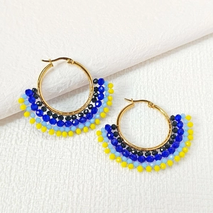 Detail of handmade beaded fan-shaped earrings with colorful beads on golden metal hoops