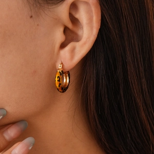 Close-up of 14k gold plated leopard print hoop earring worn on female model's ear