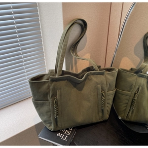Detail der olivgrünen Cord-Tasche mit gerippter Textur und Reißverschlusstaschen