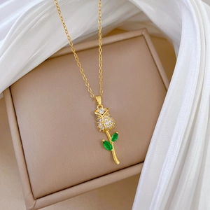 Elegant gold rose necklace with clear diamonds and green leaves on white silk