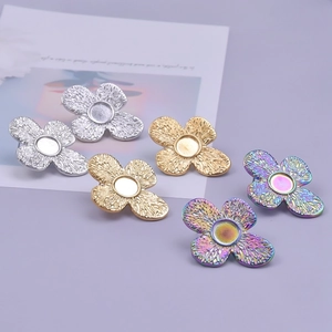 Macro view of clover-shaped stainless steel earring bases in silver gold and rainbow