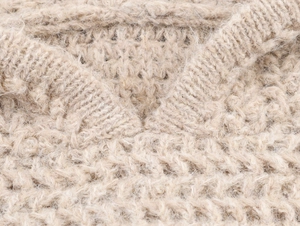 Macro view of beige chunky knit fabric texture with fuzzy mohair wool fibers