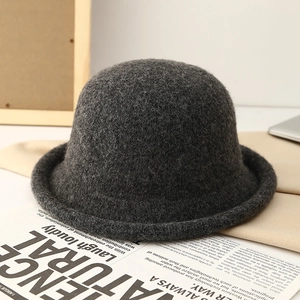 Detail shot of a dark grey knit wool bucket hat with a rolled edge on a stylish newspaper