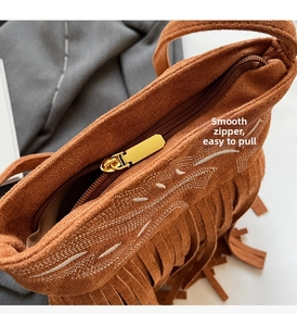 Detail of vintage brown suede bucket bag with smooth metal zipper and tassel accent