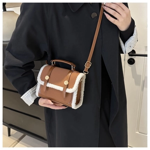 Detailed view of the brown leather handbag with plush lamb wool trim and gold metal clasp