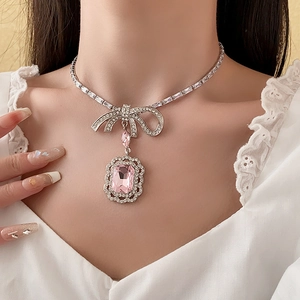 Gros plan d'un collier nœud argenté avec un grand pendentif en cristal rose rectangle