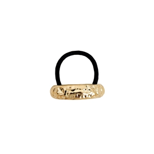 Close-up of golden hammered metal texture on black elastic hair tie with geometric design