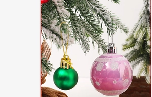 Close-up of matte green and pink glitter Christmas ball ornaments on snowy tree branches