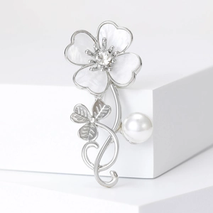 Detailed close-up of silver flower brooch with white pearl and sparkling crystals