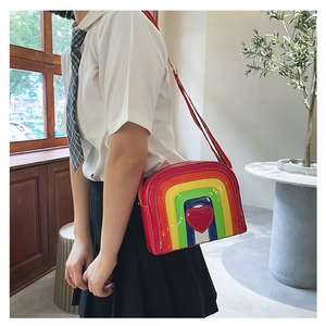 Detailed side view of a glossy rainbow crossbody bag with a red 3D heart and striped strap