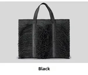 Detail of black woven straw tote bag featuring long decorative tassels and sturdy dual handles
