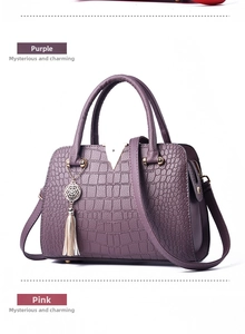 Detail of purple crocodile-patterned handbag with golden V-metal hardware and tassel
